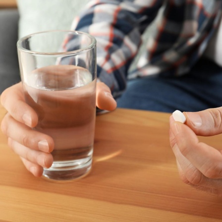 Hände mit Tablette und Wasserglas