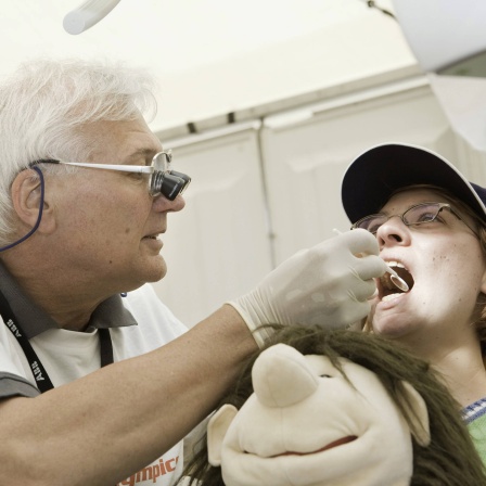 ARCHIV: Ein Zahnarzt bei den Special Olympics 2010 untersucht eine Sportlerin