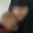 Eine mit einer Burka verschleierte Frau trägt ein Kind auf dem Arm.