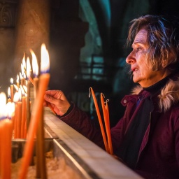 Frau zündet Kerzen in der Grabeskirche an, Jerusalem 14.12.2023; © picture alliance/Middle East Images/ABACA