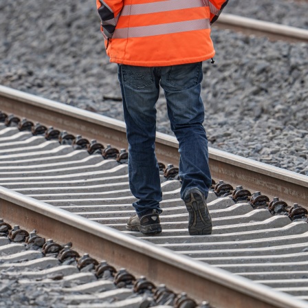 Ein Arbeiter geht auf der Riedbahnbaustelle am Bahnhof Gernsheim auf den Gleisen. (Archivbild)
