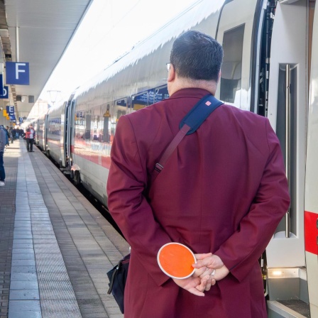Zugbegleiter am Hauptbahnhof Mannheim vor einem abfahrenden ICE (Bild: picture alliance/CHROMORANGE/Udo Herrmann)