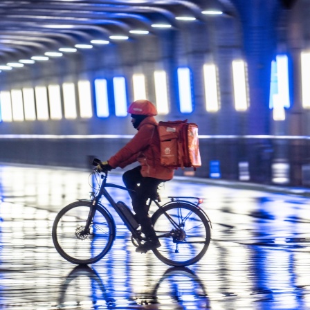 Ein Kurier eines Lieferdienstes auf dem Fahrrad.