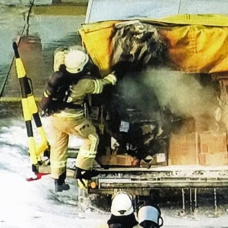 Feuerwehrleute löschen ein brennendes Paket in einem Frachtwagen am Flughafen Leipzig.