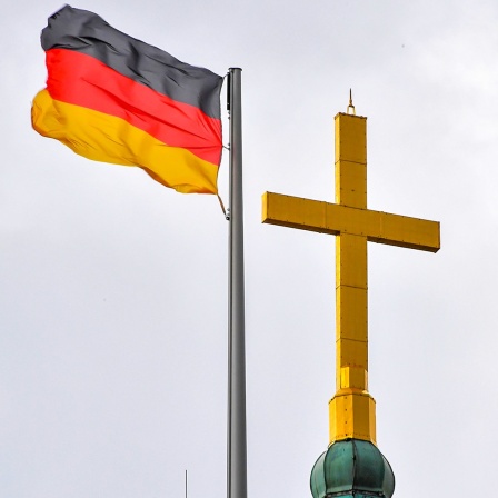 Die Flagge der Bundesrepublik weht neben dem Turmkreuz der Wartburg.