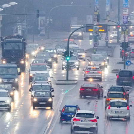Die Lichter der Scheinwerfer der auf der Breiten Straße in der Potsdamer Innenstadt fahrenden Autos und LKW werden am Morgen von der regennassen Straße reflektiert. (Bild: picture alliance/dpa /Sören Stache)