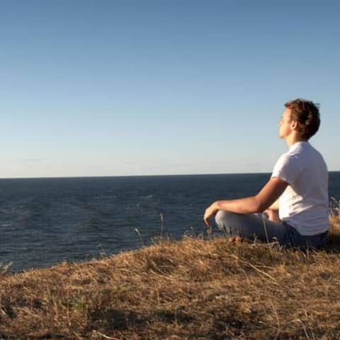 Ein Mann sitzt am Meer und meditiert