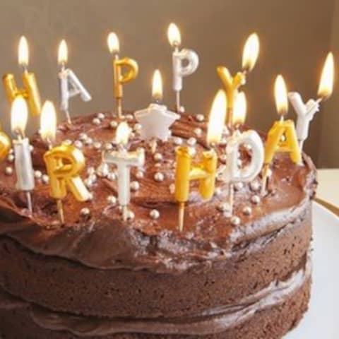 Schokoladenkuchen mit Kerzen in Form von "Happy Birthday"