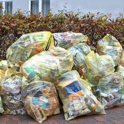 In Schleswig liegen auf einem Gehweg Gelbe Säcke mit Plastikmüll zur Abholung bereit.