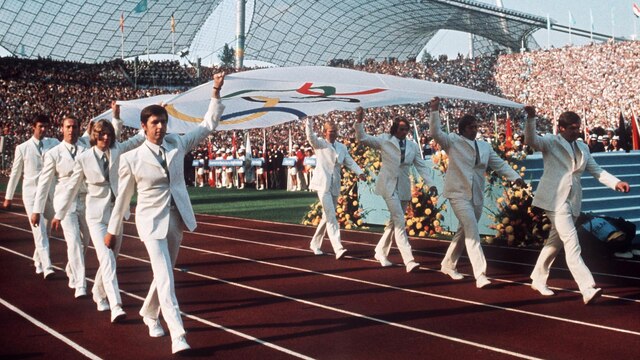 Das Archivbild vom 26.08.1972 zeigt die Mannschaft des bundesrepublikanischen Gold-Achters (Rudern) von Mexiko 1968, die die Olympische Fahne bei der Eröffnungsfeier in das Münchner Olympiastadion trägt. | Bild: picture-alliance / dpa/dpaweb