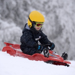 Ein Junge fährt mit seinem Schlitten durch den Schnee.