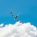 Symbolbild: Langstreckenflugzeug fliegt über eine Wolke in den blauen Himmel