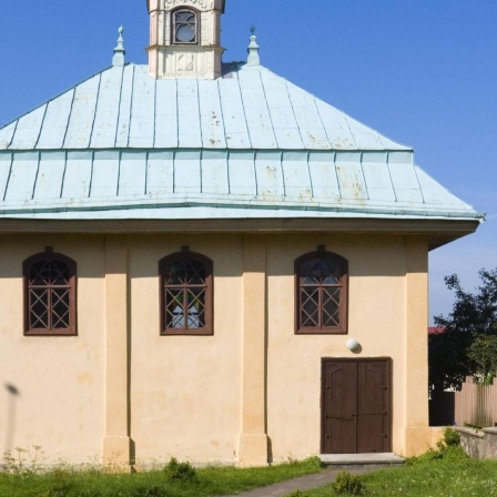 Blick auf das Kenesa-Gebetshaus in Trakai: ein blaßgelb gestrichenes Gebäude mit grünem Dach und braunen Türen und Fensterrahmen.