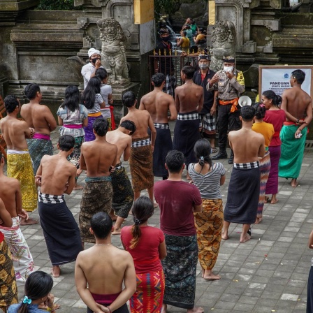 Menschen in Indonesien stehen vor dem Eingang zu einer heiligen Quelle mit Abstand in mehreren Reihen (Bild: imago images / ZUMA Wire)
