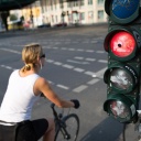 Eine Radfahrerin fährt über eine rote Ampel. Die Aufnahme zeigt die Bewegung, es ist ein verwischtes Foto.