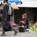 Eine Straßenszene in Äthiopiens Haupststadt Addis Abeba: Eine Frau sitzt am Straßenrandd und verkauft Früchte. Ein männlicher Passant eilt vorbei. 