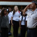 Schülerinnen und Schüler stehen stramm vor einem Offizier in Uniform, der in Richtung Fahne (nicht im Bild) salutiert