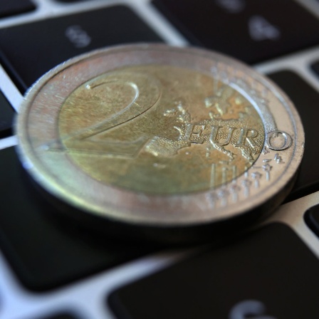 Eine Zwei-Euro-Münze liegt auf der Tastatur eines Laptops.