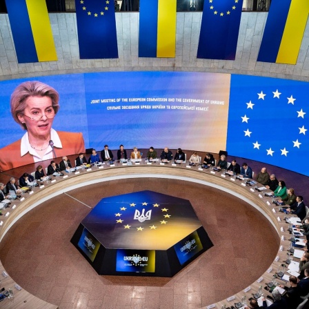 Die Präsidentin der EU-Kommission, Ursula von der Leyen, ist auf einem Bildschirm während des EU-Ukraine-Gipfels in Kiew zu sehen, die Teilnehmer sitzen an einem runden Tisch davor.