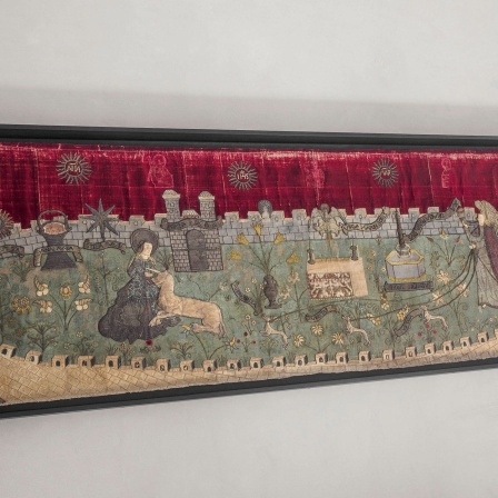 Einhornjagd Antipendium. Der verschlossene Garten. Es geht eine Mauer drum-herum und in der Mitte ist Wiese. Auf der Wiese findet eine Jagd statt. Der Stoff hängt im Museum Kolumba, Köln