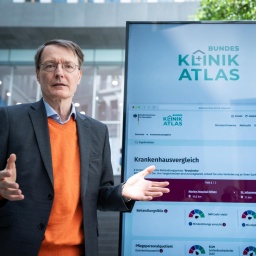 Bundesgesundheitsminister Lauterbach (SPD) steht neben einem Bildschirm, auf dem das neue Klinikatlas-Portal zu sehen ist