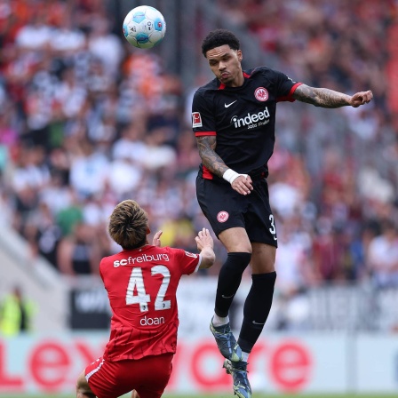 Ritsu Doan vom SC Freiburg gegen Pharell Nnamdi Collins von Eintracht Frankfurt 