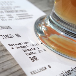 Der Fuß eines Hefeweizenglases steht auf einer Restaurantrechnung über Hefeweizen-Bier.