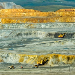 Blick in ein Tagebau-Kupferbergwerk in der Mongolei, in dem mehrere Bagger und Fahrzeuge zu sehen sind.