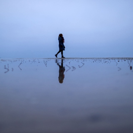 Eine Frau läuft am Meer entlang