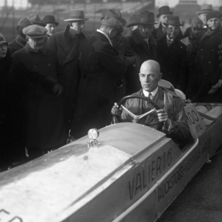 Schwarz-weiß-Aufnahme von Max Valier im Raketenauto, drum herum stehen Menschen 