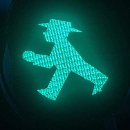 Ein Grünes Ampelmännchen leuchtet an der Ampel.