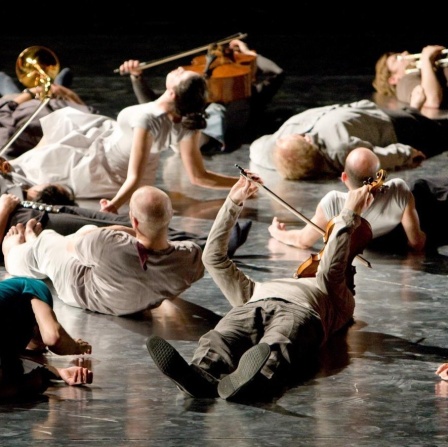 Mitglieder des Ensemble Modern spielen liegend bei der Uraufführung von Wolfgang Rihms "Jagden und Formen".
