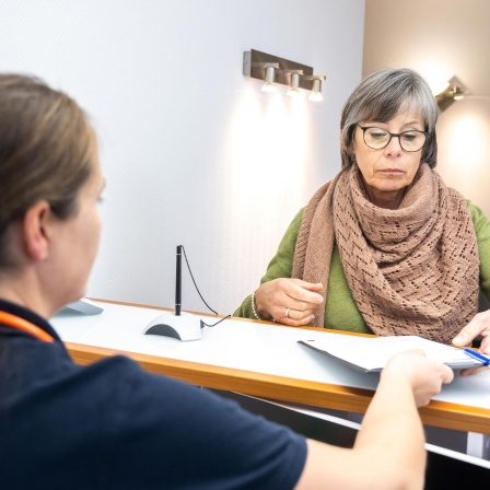 Eine Patientin wird in einer Praxis von einer Sprechstundenhilfe beraten.