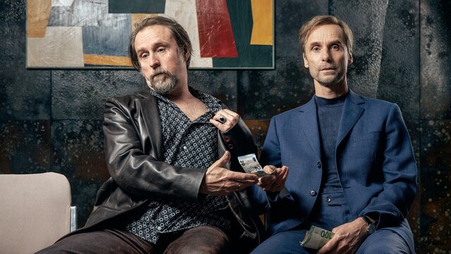 Szenenbild aus der Impro-Serie "Kranitz - Bei Trennung Geld zurück": Zwei Männer sitzen nebeneinander auf Stühlen und halten Geld in der Hand.