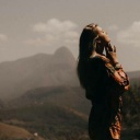 Frau steht mit geschlossenen Augen vor einer Berglandschaft