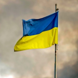 Die ukrainische Flagge ist vor dem Rauch eines Feuers zu sehen, nach russischen Angriffen auf Kiew.