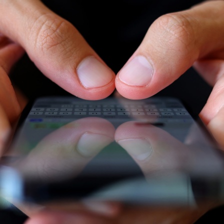 Ein Mann hält ein Smartphone in seinen Händen