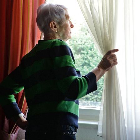 Eine ältere Frau sieht aus dem Fenster