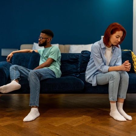 Ein Paar sitzt getrennt auf einem Sofa und sieht unglücklich aus, sie reden nicht miteinander