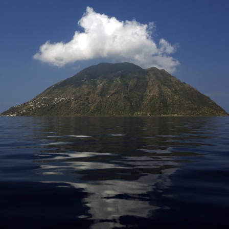 Blick auf die Insel Alicudi im Meer über der eine weiße Wolke schwebt