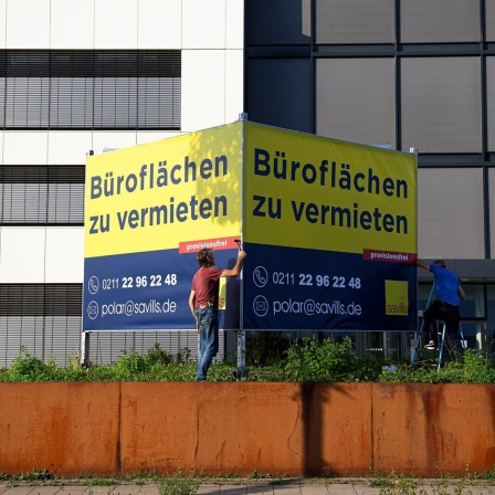 Arbeiter stellen in Düsseldorf ein Schild auf "Büroflächen zu vermieten".