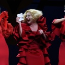 Szenenfoto aus "Die Wahrheit über Leni Riefenstahl": Drei blonde Frauen in roten Kleidern stehen als Gruppe zusammen und lachen.