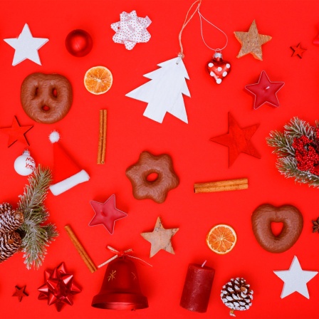Weihnachtsdeko, Kerzen und Kekse auf rotem Hintergrund. 