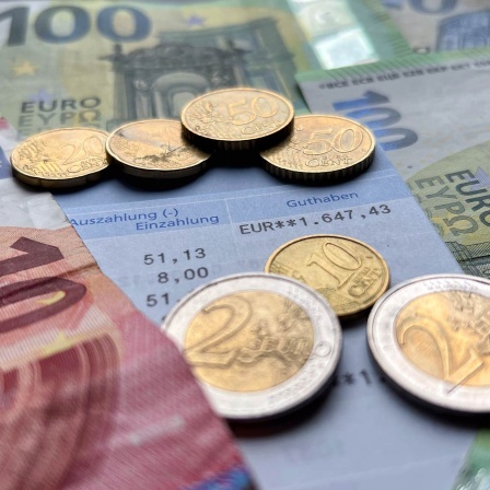 Euroscheine und -münzen liegen auf einem Kontoauszug. 