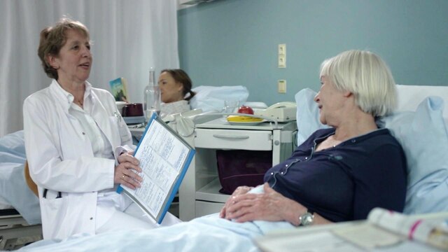 Eine Ärztin spricht mit einer Patientin in einem Krankenhausbett.