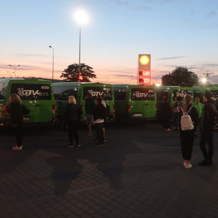 Reisende stehen auf dem Busparkplatz Port Katy in Polen. 