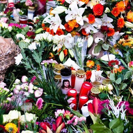 Blumen und Kerzen liegen vor der Johanniskirche in der Nähe des Weihnachtsmarkts in Magdeburg.
