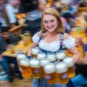 Eine Kellnerin auf dem Oktoberfest trägt mehrere Maß Bier aus.