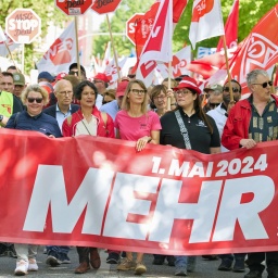 Demonstranten halten ein Transparent mit der Aufschrift "1.Mai 2024 Mehr Lohn, Freizeit, Sicherheit" in Hamburg-Altona.