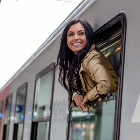 Eine Frau schaut aus dem Fenster eines Zuges im Bahnhof
